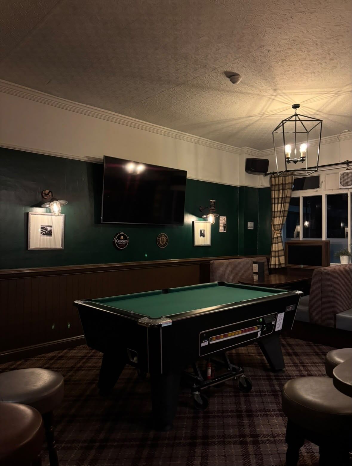 The games corner at O'Farrell's: pool table under a low light with a big screen on the wall behind